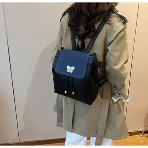 Detail of backpack with butterfly buckle, denim patchwork, and black pebbled leather