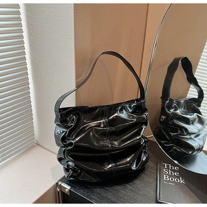 Dettaglio della borsa a spalla nera lucida con design a pieghe e finiture in metallo argento