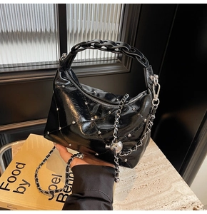 Detail of black quilted leather bag with silver rivets and chunky chain handle
