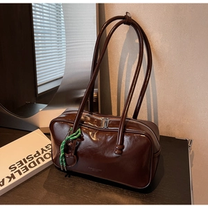Détail du sac bowling marron chocolat en cuir ciré brillant avec un nœud vert décoratif