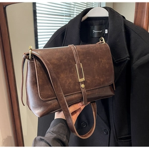 Detail showing the brown vintage PU leather texture and golden metal buckle of the bag
