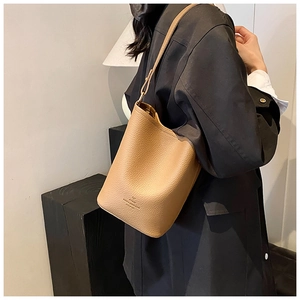Detail of tan leather bucket bag showing embossed logo and adjustable shoulder strap