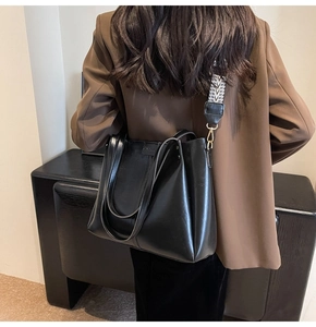 Détail du sac cabas noir avec une bandoulière tissée géométrique et des boucles dorées