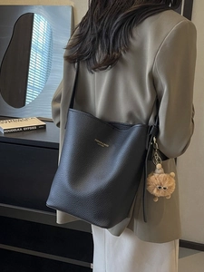 Classic black leather bucket bag for women with a luxury pom-pom and gold lettering