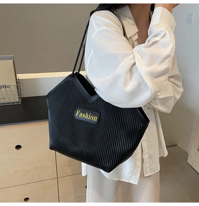Close-up of black pleated tote bag featuring a yellow Fashion logo and fine texture