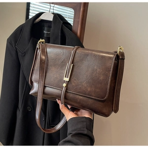 Macro view of vintage brown leather bag showing oily texture and gold metal buckle detail
