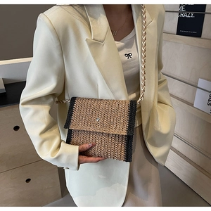 Dettaglio della borsa a tracolla in paglia intrecciata con bordo a contrasto su blazer