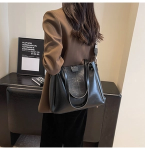 Détail d'un sac cabas en cuir noir avec bandoulière jacquard et rivets métalliques