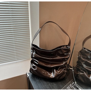 Dettaglio di una borsa a spalla marrone scuro lucido con pieghe e texture vintage retro