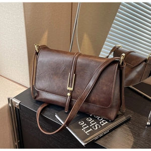 Detail of vintage dark brown faux leather crossbody bag with golden metal hardware
