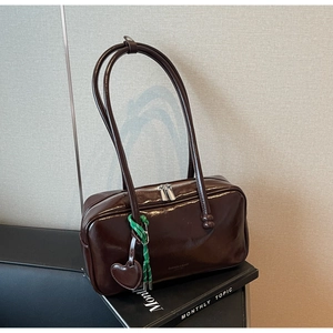 Détail du sac bowling vintage marron avec doubles poignées et breloque cœur en cuir