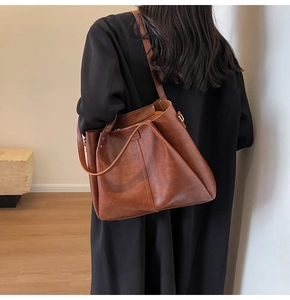 Détail d'un grand sac cabas marron avec doubles anses et bandoulière réglable chic