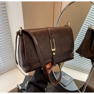 Close-up of a vintage dark brown leather crossbody bag with golden hardware and flap detail