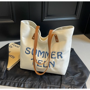 Détail du sac fourre-tout en toile blanche avec broderie Summer Teln bleue et anses brunes