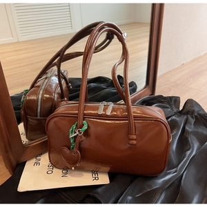 Vue détaillée d'un sac bowling vintage marron avec un pendentif cœur tissé vert
