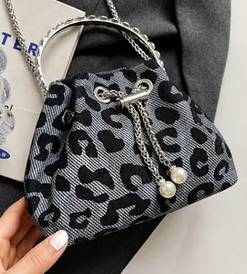 Detail of grey leopard bucket bag with silver metal ring handle and pearl drawstring charms