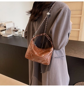 Detail of brown quilted shoulder bag with metallic rivets and elegant chain strap