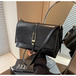 Close-up of black vintage textured crossbody bag with elegant gold U-shaped metal lock