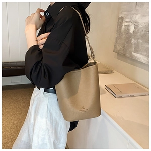 Detail of khaki pebbled leather bucket bag with bow print and Paris text on side