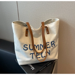 Détail de la broderie SUMMER TELN bleue et des anses en cuir marron sur le cabas beige