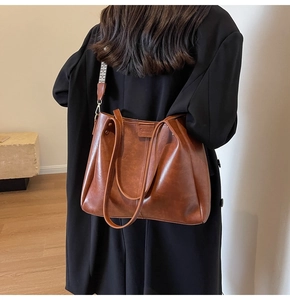 Sac fourre-tout marron avec bandoulière large sur manteau noir pour usage quotidien