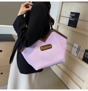 Detail of light purple pleated tote bag with brown trim and Fashion logo plate