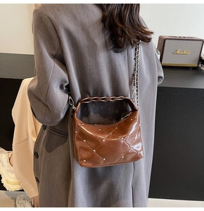 Brown patent leather quilted crossbody bag with silver studs worn with a grey blazer