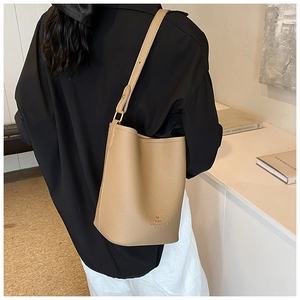 Close-up of lychee grain leather bucket bag featuring gold logo and bow detail
