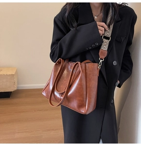 Gros plan d'un cabas en cuir marron avec bandoulière large à motifs géométriques et boucle
