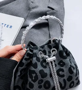 Detailed view of silver crystal-encrusted metal handle on leopard print bucket bag