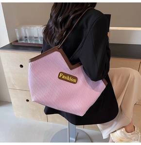 Detail of pink pleated tote bag with dark brown leather handles and fashion label