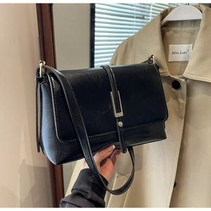 Close-up of black matte PU leather bag with gold rectangular clasp and slim shoulder strap