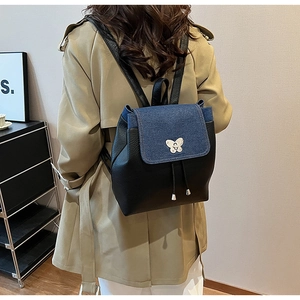 Women's chic denim and black leather backpack with butterfly buckle on a female model