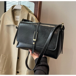 Detail of vintage black crossbody bag with gold metal clasp and pleated leather texture
