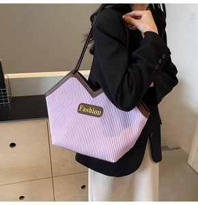 Detailed close-up of purple pleated tote bag with brown leather trim and fashion plaque