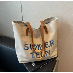 Détail du grand sac cabas en toile avec broderie chenille bleue et poignées en cuir