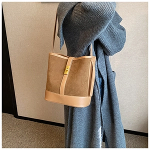 Detail of brown faux suede bucket bag featuring a gold square twist lock on grey knitwear