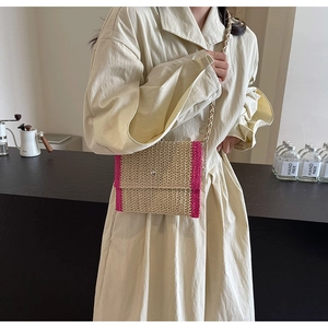 Dettaglio della borsa a tracolla in paglia intrecciata con finiture rosa e catena