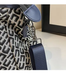 Detail of silver metal hook and blue nylon strap on jacquard fabric travel bag