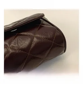 Macro detail of dark brown quilted leather surface with glossy finish and precise stitching