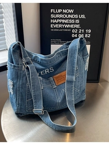 Vintage Denim Umhängetasche mit weißen Nähten und verstellbarem Gurt auf einem Metalltisch