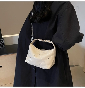 Detail of off-white quilted bag with silver rivets, chain strap and woven handle