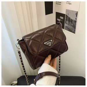 Detail of dark brown quilted crossbody bag featuring glossy leather and triangular metal logo