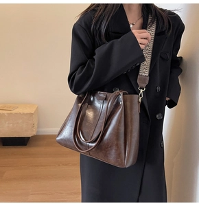 Détail du sac cabas marron vintage avec bandoulière tissée sur un blazer noir