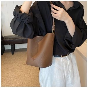 Close-up of brown leather bucket bag with lychee texture and metallic gold hardware
