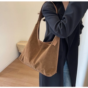 Macro detail of brown suede hobo bag showing vertical double stitching and soft texture