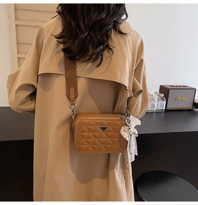 Detailed back view of brown quilted leather camera bag with wide fabric strap and lace charm