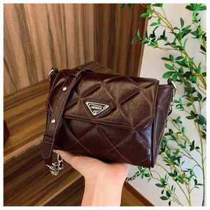 Detailed view of dark brown quilted crossbody bag with triangle logo and silver chain strap