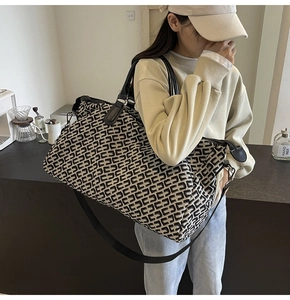 Black and white geometric travel tote bag with adjustable strap in a lifestyle setting