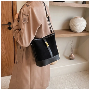 Detail of black faux suede bucket bag with gold metal buckle shown on a model's shoulder